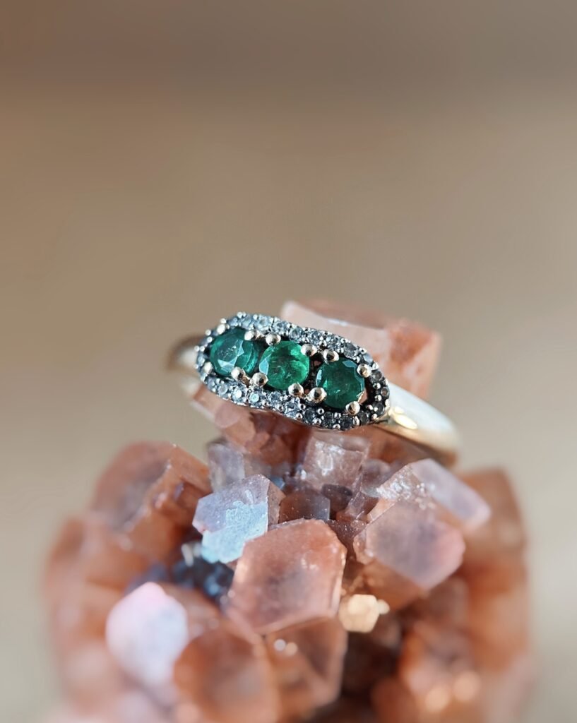 Vintage 9 karaat massief gouden ring met drie smaragden omringd met een rij van diamanten