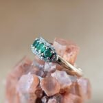 Vintage 9 karaat massief gouden ring met drie smaragden omringd met een rij van diamanten