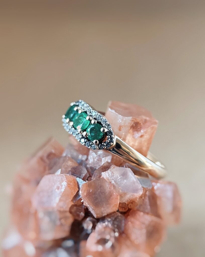 Vintage 9 karaat massief gouden ring met drie smaragden omringd met een rij van diamanten