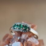 Vintage 9 karaat massief gouden ring met drie smaragden omringd met een rij van diamanten