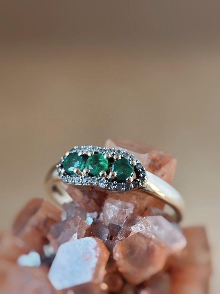 Vintage 9 karaat massief gouden ring met drie smaragden omringd met een rij van diamanten