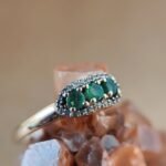 Vintage 9 karaat massief gouden ring met drie smaragden omringd met een rij van diamanten