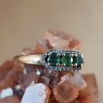 Vintage 9 karaat massief gouden ring met drie smaragden omringd met een rij van diamanten
