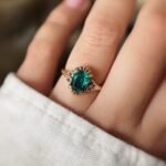 Vintage 9K gold ring with an emerald-cut green stone worn on a finger