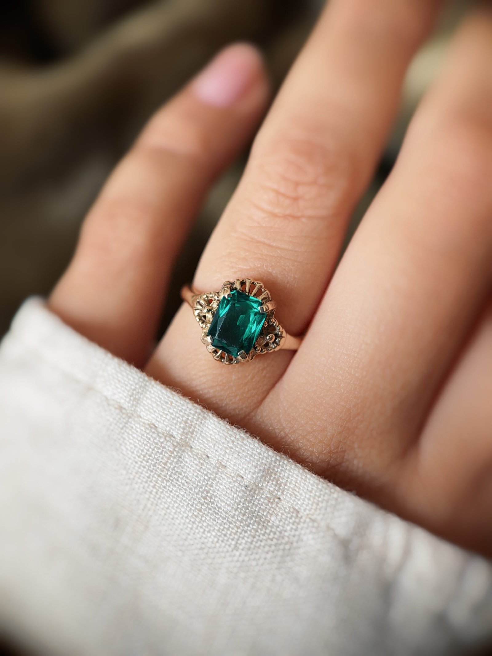 Vintage 9K gold ring with an emerald-cut green stone worn on a finger