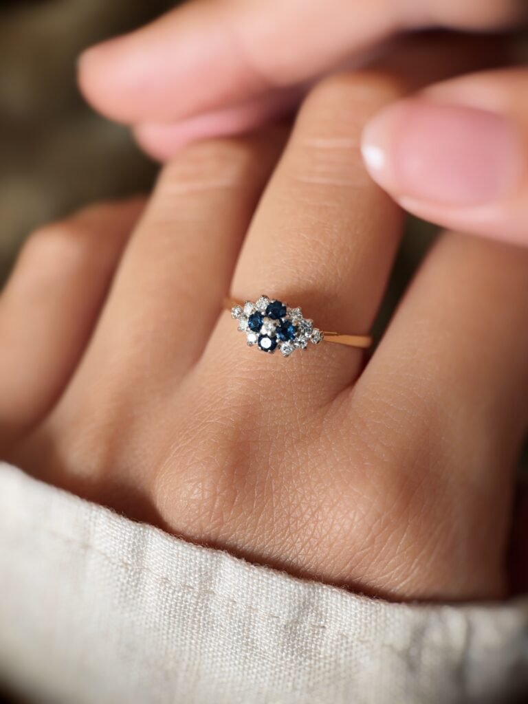 Vintage 18K gold sapphire and diamond cluster ring worn on a finger
