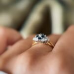 Vintage 18K gold sapphire and diamond cluster ring worn on a finger