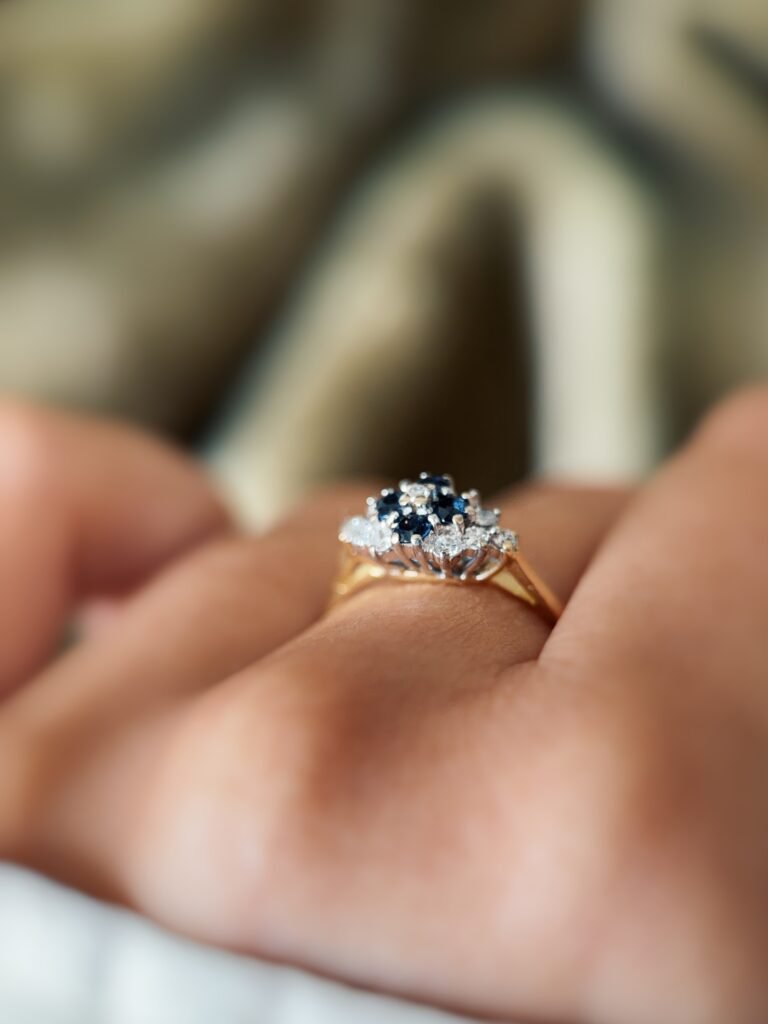 Vintage 18K gold sapphire and diamond cluster ring worn on a finger
