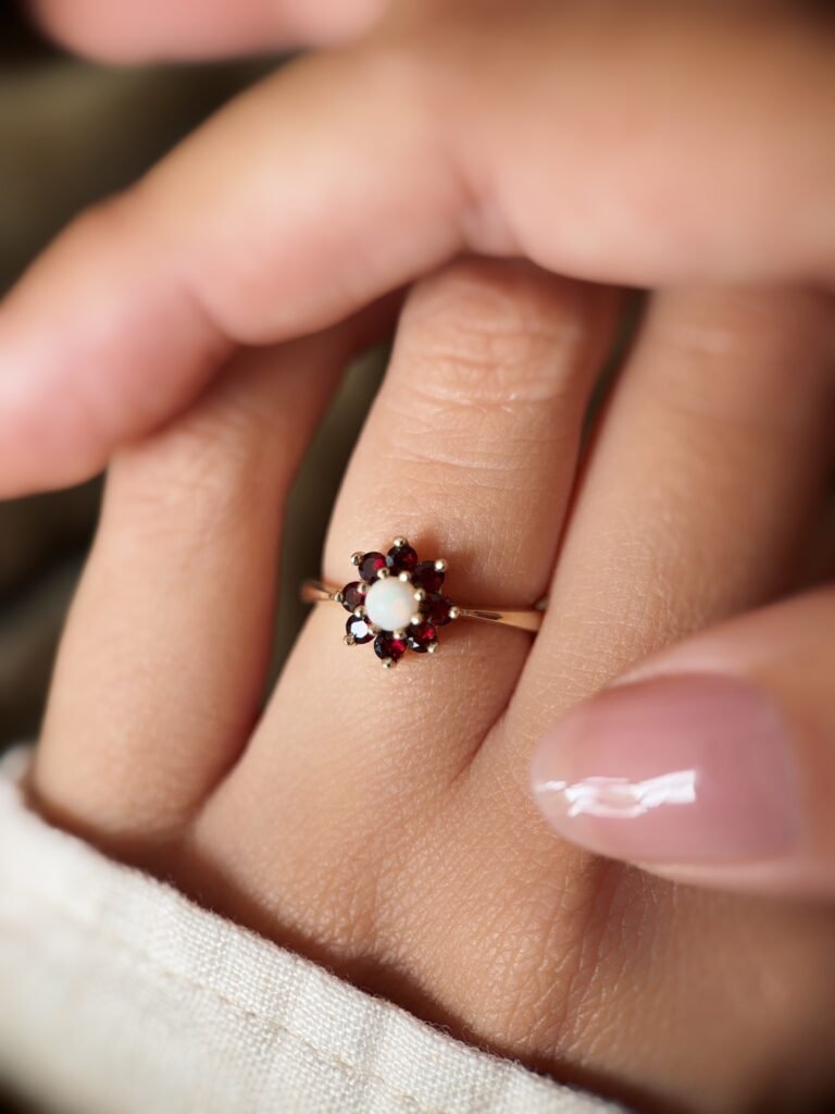 Vintage 9K gold opal and garnet cluster ring worn on a finger