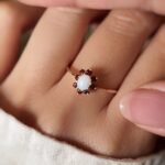 Vintage gold ring with oval opal and red garnets worn on a hand