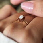 Vintage gold ring with oval opal and red garnets worn on a hand