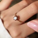 Vintage gold ring with oval opal and red garnets worn on a hand