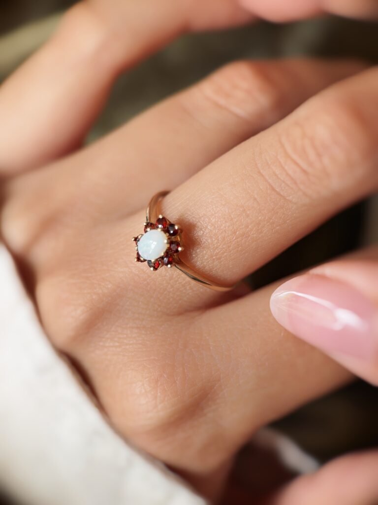 Vintage gold ring with oval opal and red garnets worn on a hand