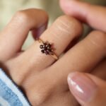 Vintage 9 carat gold garnet daisy flower ring worn on a hand