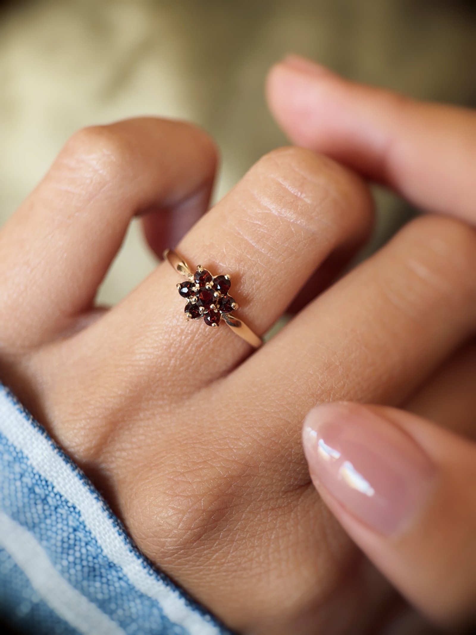 Vintage 9 carat gold garnet daisy flower ring worn on a hand