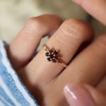 Vintage 9 carat gold garnet daisy flower ring worn on a hand