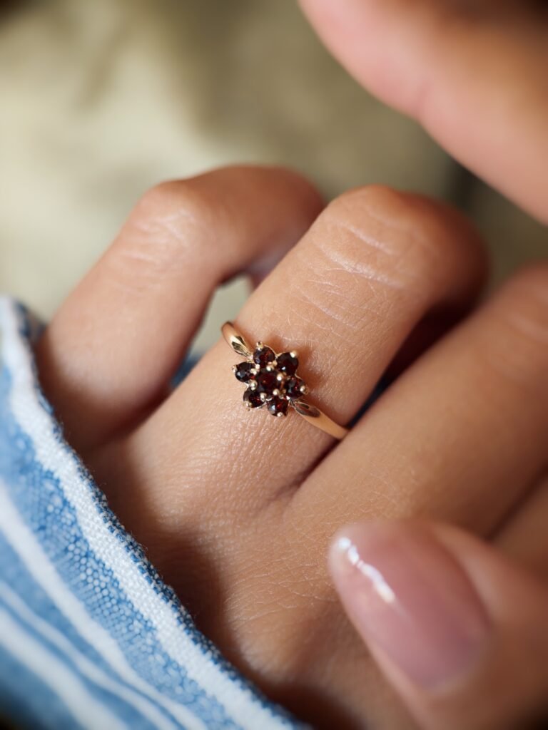 Vintage 9 carat gold garnet daisy flower ring worn on a hand