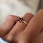 Vintage 9 carat gold garnet daisy flower ring worn on a hand