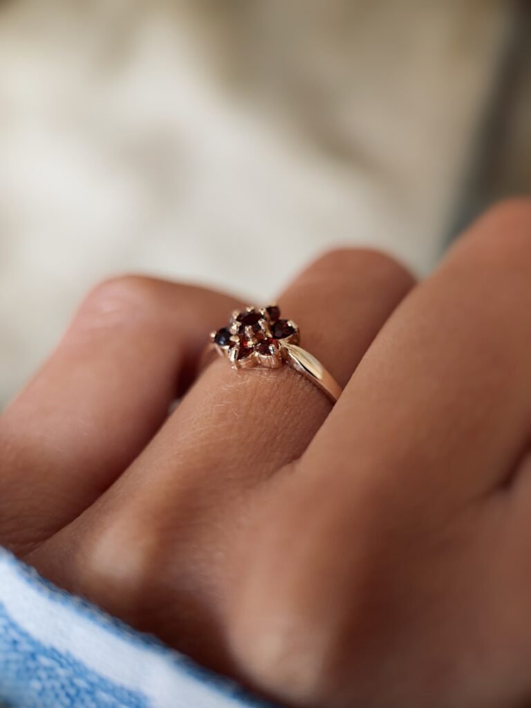 Vintage 9 carat gold garnet daisy flower ring worn on a hand