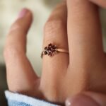 Vintage 9 carat gold garnet daisy flower ring worn on a hand