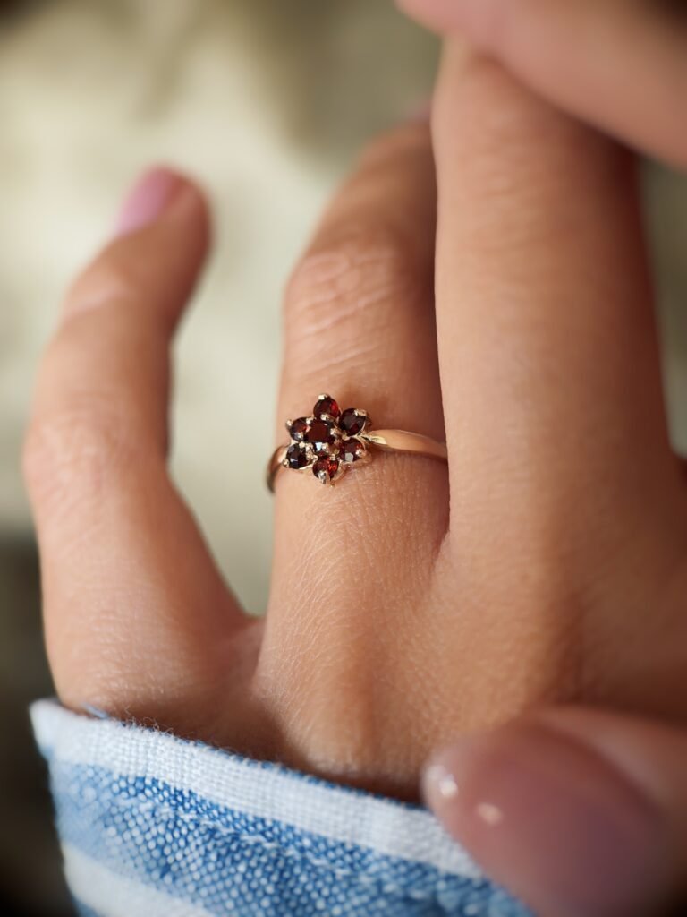 Vintage 9 carat gold garnet daisy flower ring worn on a hand