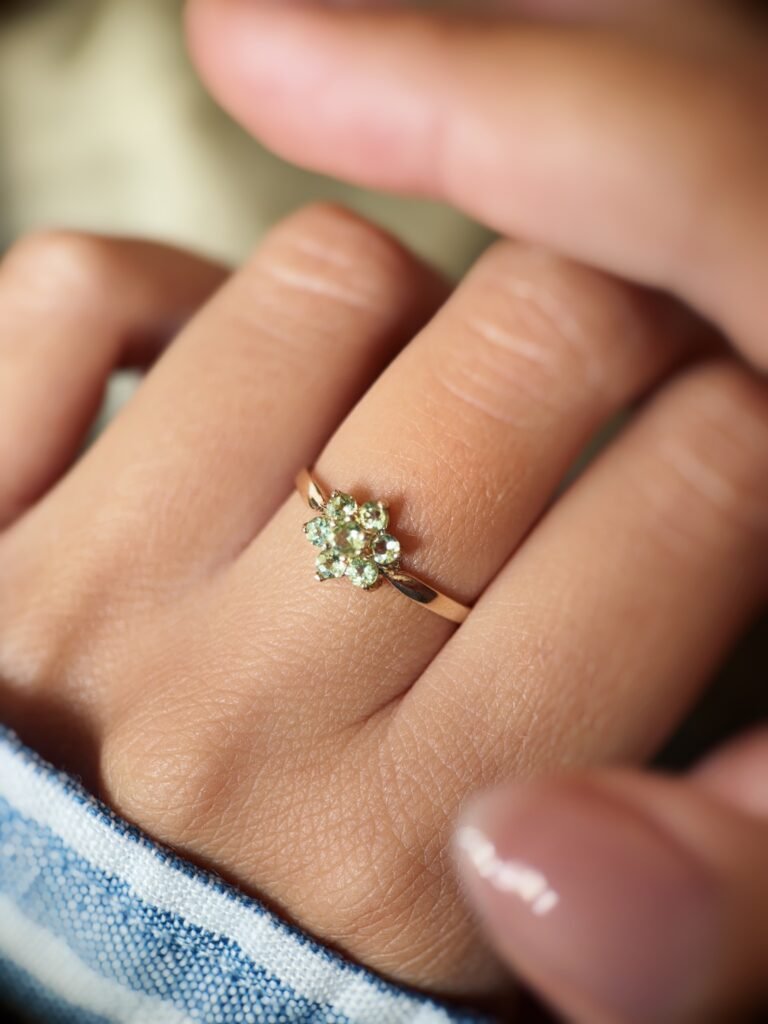 Vintage 9 carat gold daisy flower ring with peridot worn on a hand