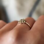 Vintage 9 carat gold daisy flower ring with peridot worn on a hand