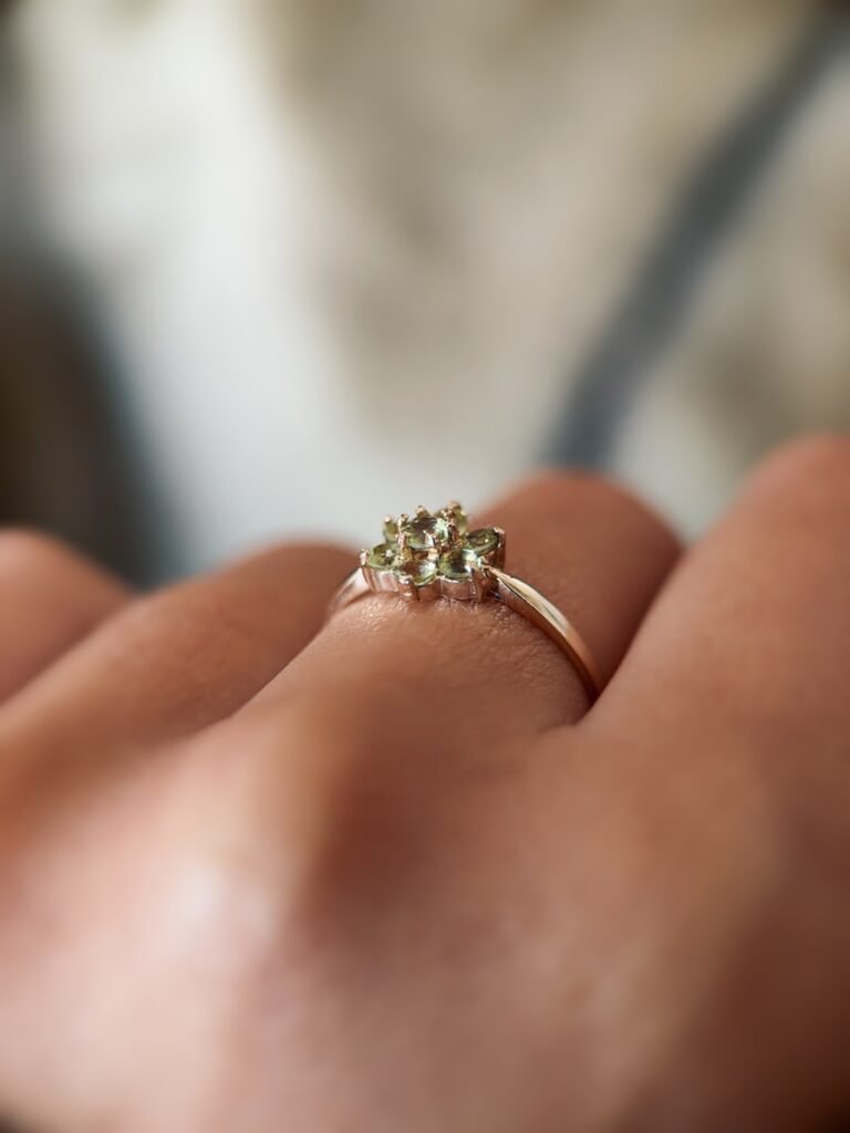 Vintage 9 carat gold daisy flower ring with peridot worn on a hand