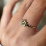 Vintage 9 carat gold daisy flower ring with peridot worn on a hand