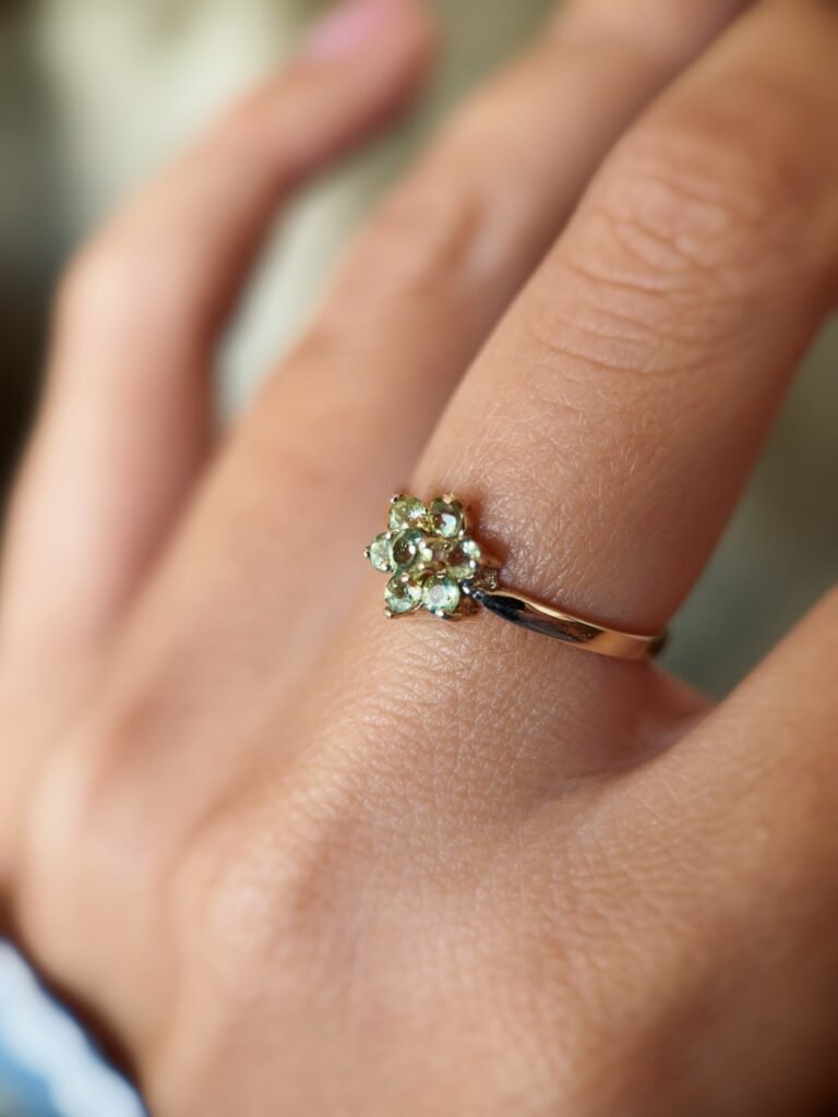 Vintage 9 carat gold daisy flower ring with peridot worn on a hand