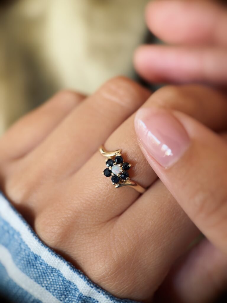 Vintage 9 carat gold sapphire and opal daisy flower ring worn on a hand