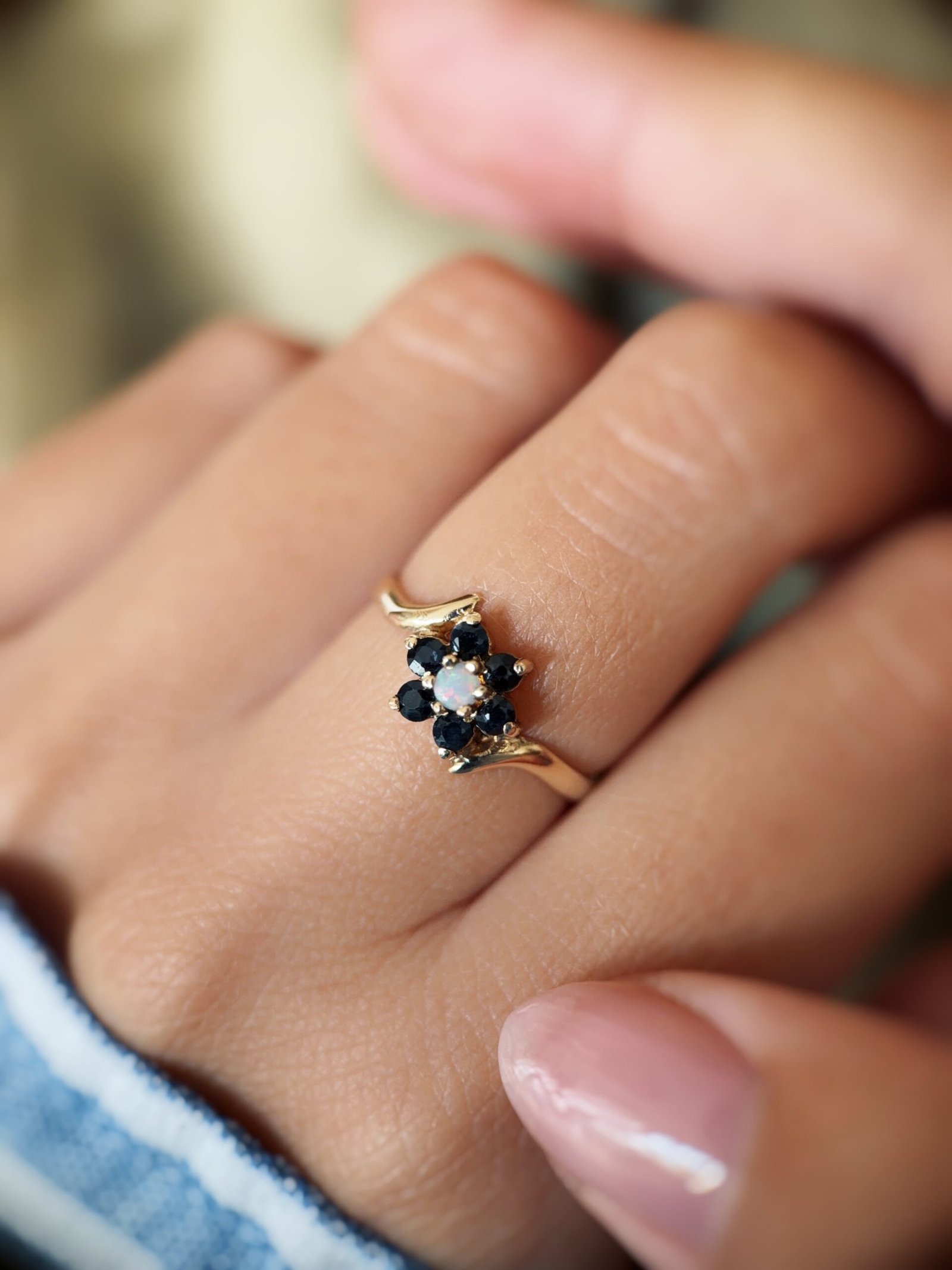 Vintage 9 carat gold sapphire and opal daisy flower ring worn on a hand