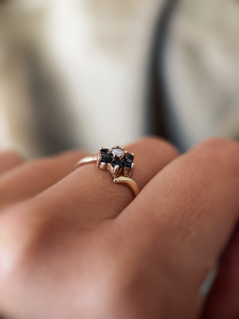 Vintage 9 carat gold sapphire and opal daisy flower ring worn on a hand