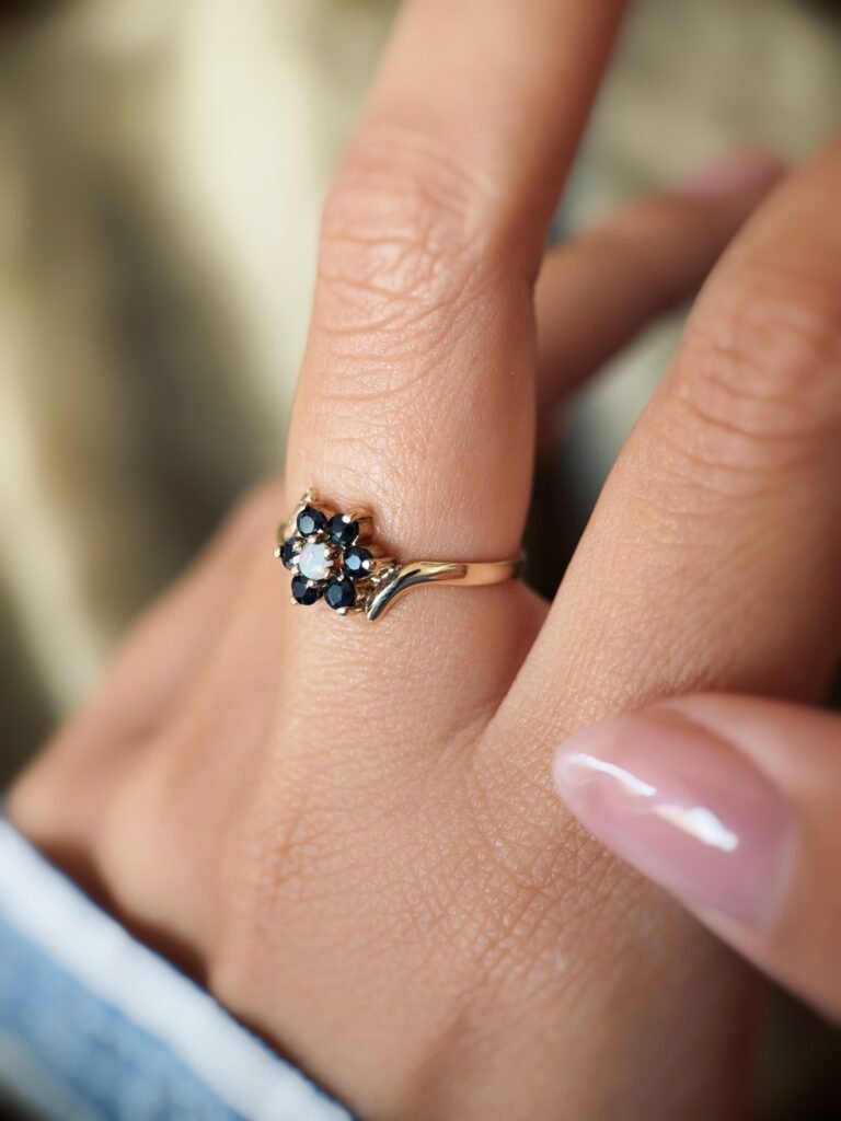 Vintage 9 carat gold sapphire and opal daisy flower ring worn on a hand