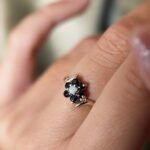 Vintage 9 carat gold sapphire and opal daisy flower ring worn on a hand
