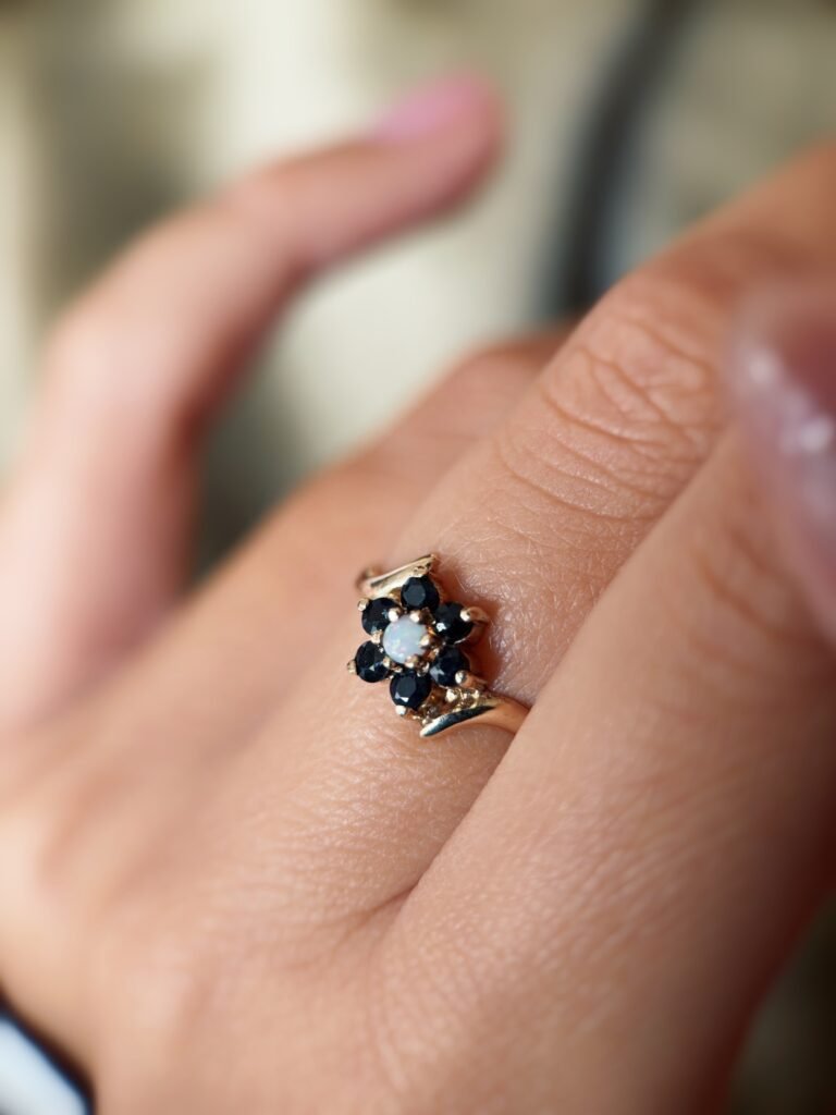 Vintage 9 carat gold sapphire and opal daisy flower ring worn on a hand