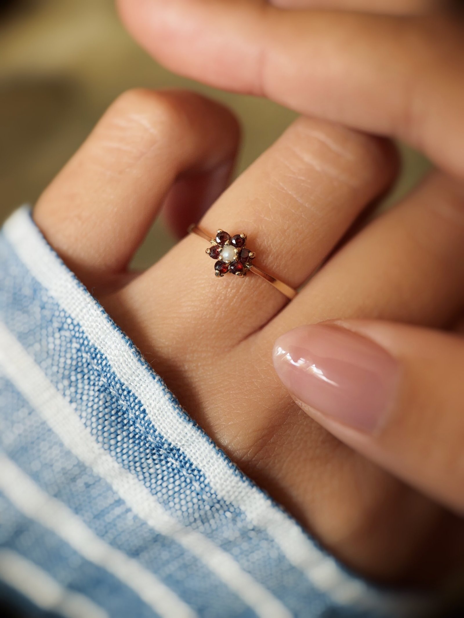 Vintage 9 carat gold pearl and garnet daisy ring worn on a hand