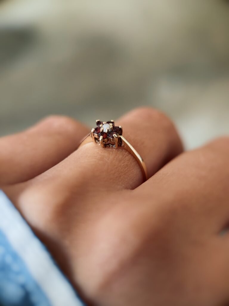 Vintage 9 carat gold pearl and garnet daisy ring worn on a hand