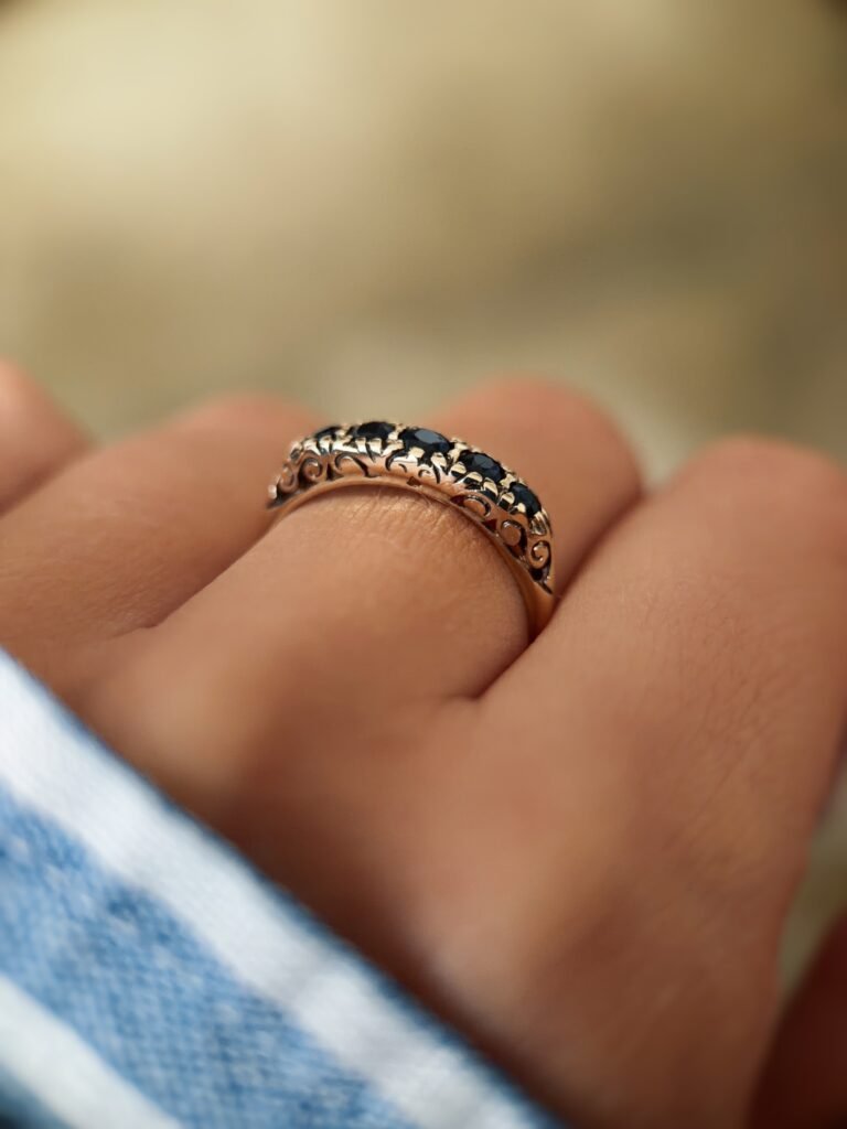 Vintage 9 carat gold five stone sapphire ring worn on a hand