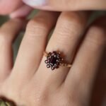 Vintage 9 carat gold dark red garnet cluster ring worn on a hand