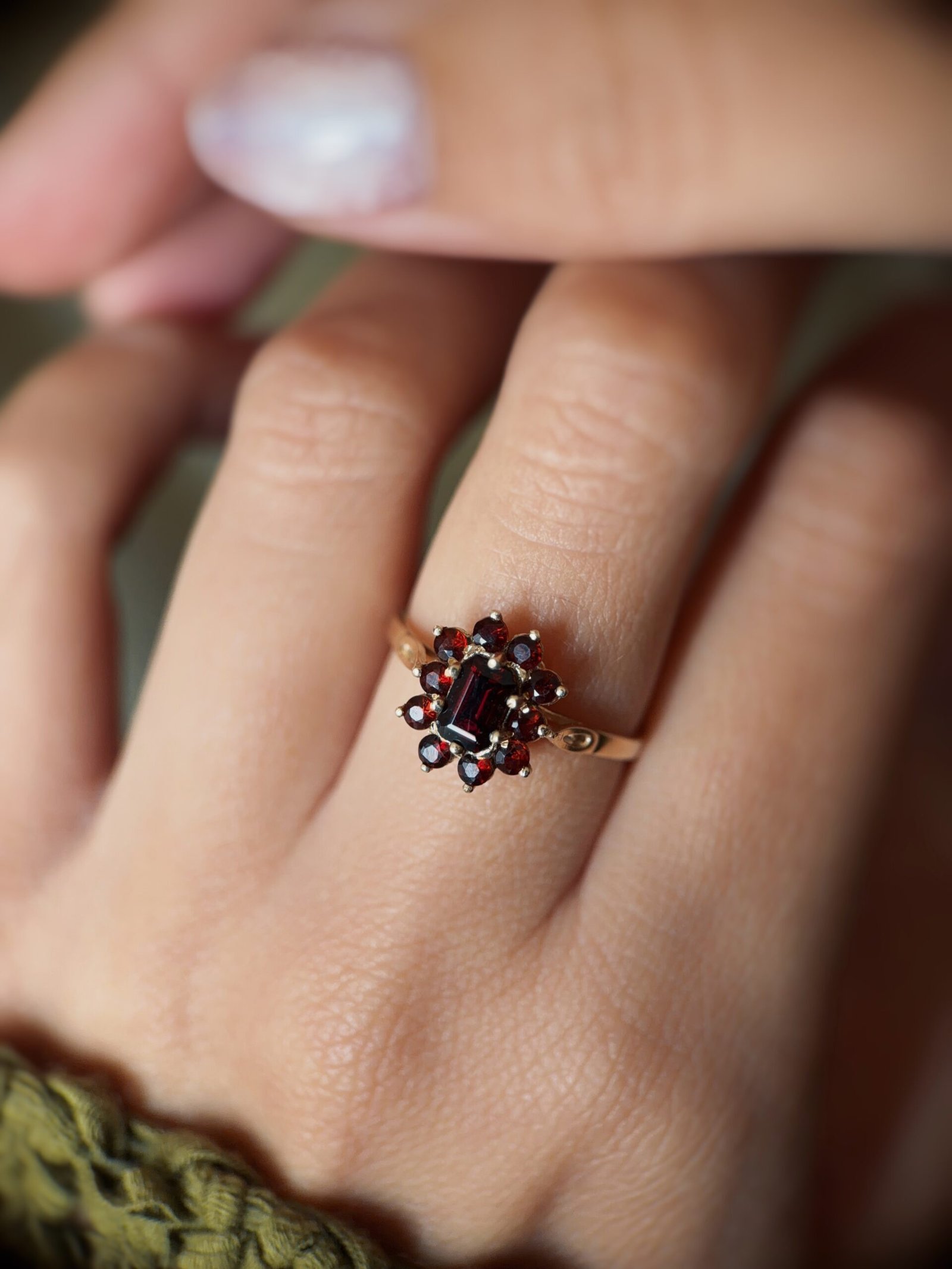 Vintage 9 carat gold dark red garnet cluster ring worn on a hand