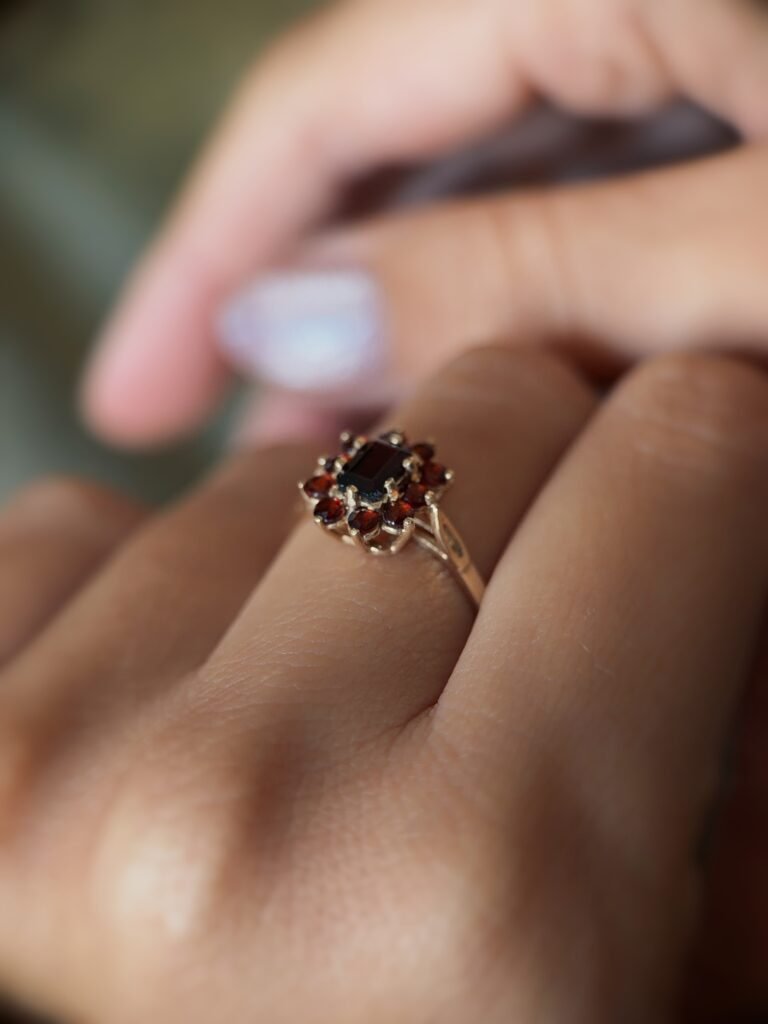Vintage 9 carat gold dark red garnet cluster ring worn on a hand