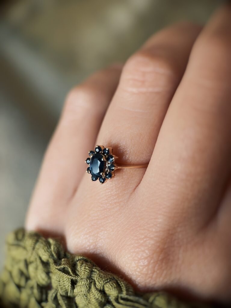 Vintage 9 carat gold dark blue sapphire cluster ring worn on a hand