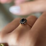 Vintage 9 carat gold dark blue sapphire cluster ring worn on a hand