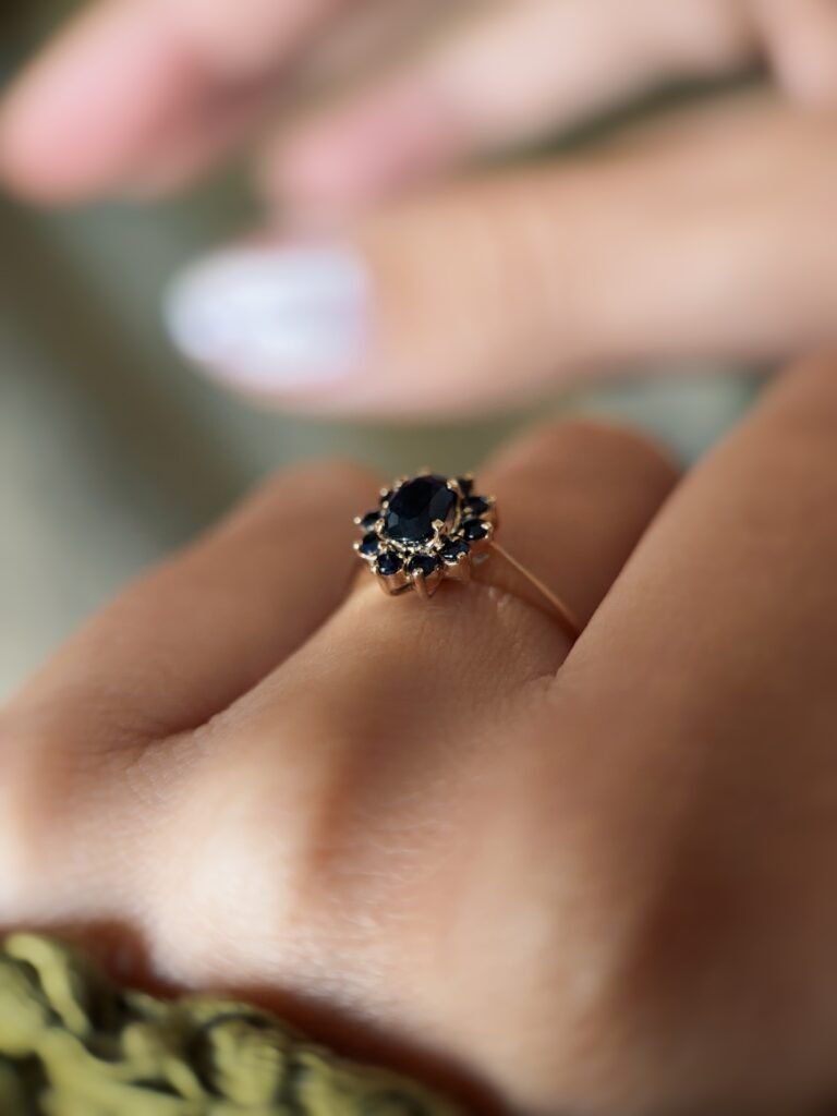 Vintage 9 carat gold dark blue sapphire cluster ring worn on a hand