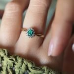 Vintage gold diana ring with oval emerald and diamonds worn on a hand