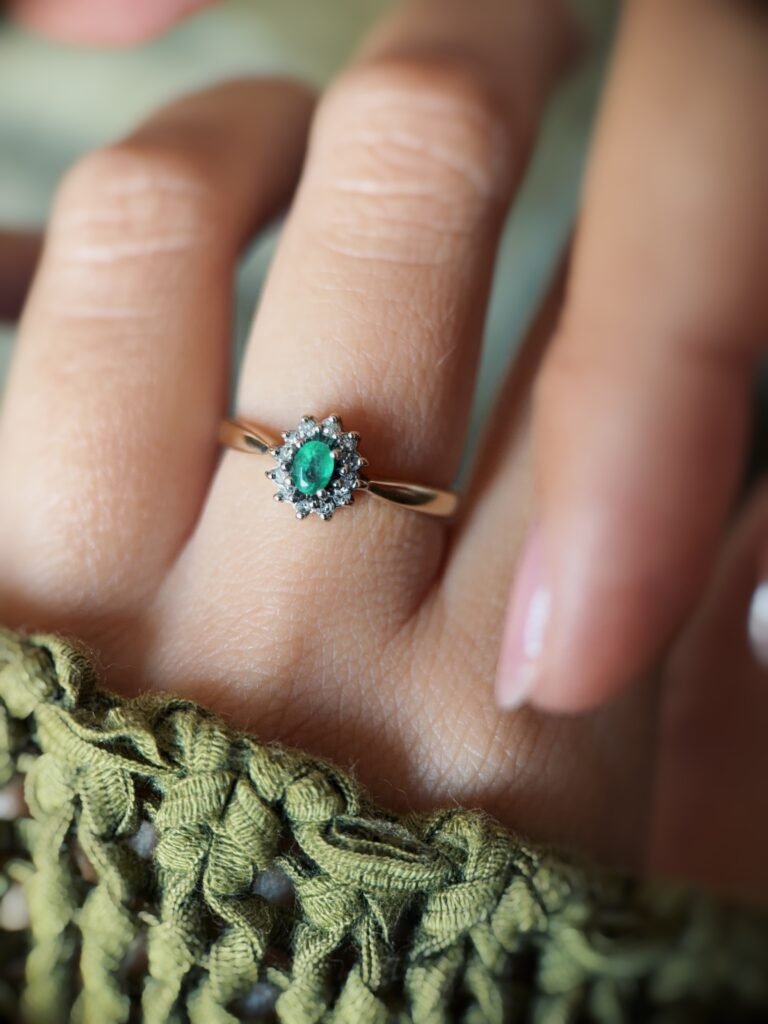 Vintage gold diana ring with oval emerald and diamonds worn on a hand