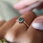 Vintage gold diana ring with oval emerald and diamonds worn on a hand