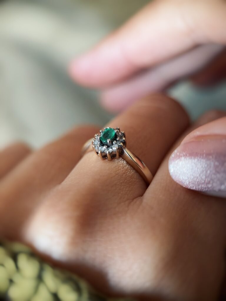 Vintage gold diana ring with oval emerald and diamonds worn on a hand
