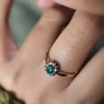 Vintage gold diana ring with oval emerald and diamonds worn on a hand